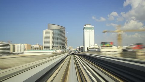 Dubai metro POV time lapse view from rear cabin. Train quickly ride from BurJuman underground station, at red line, pass downtown area and Business Bay overground station. Blue sky with light clouds
