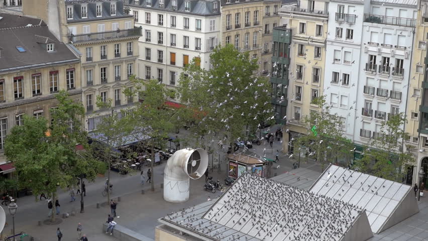 Slow motion of flock of pigeons flying over the square and sitting on the building roof by the Centre Georges Pompidou in Paris, France