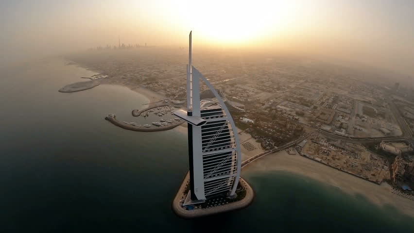Fly over Jumeirah Beach near Burj Al Arab hotel in Dubai, UAE. Burj Al Arab is a luxury 5 star hotel built on an artificial island in front of Jumeirah beach. Helicopter aerial view at sunrise
