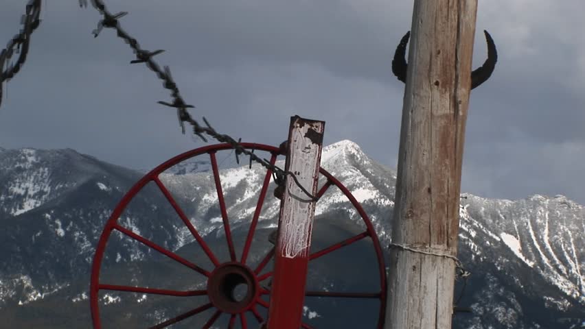 MS - Red wagon-wheel rim, barbed-wire, cattle horns tacked to a pole.