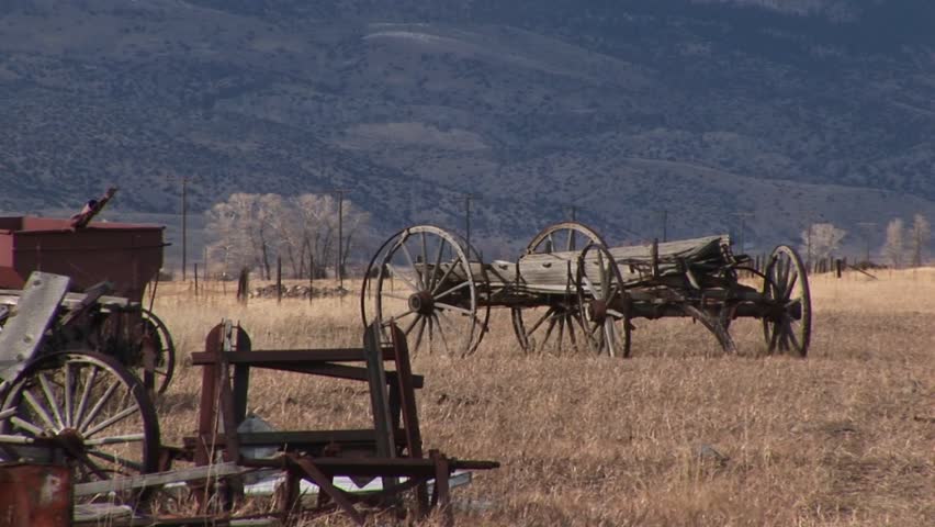 Abandoned farm wagon on prairie with foothills in background
