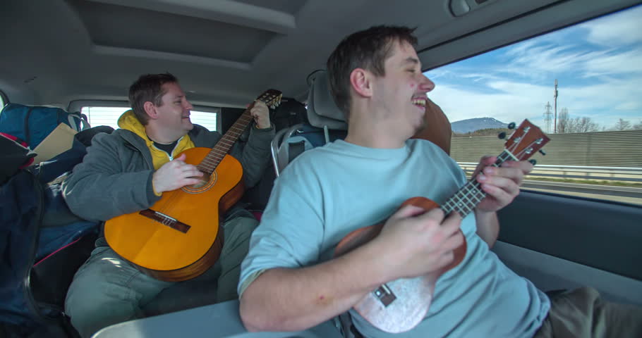 Two guys are playing their guitars in the van when the vehicle is moving. They're having a lot of fun practicing. Close-up shot. | Shutterstock HD Video #15536389