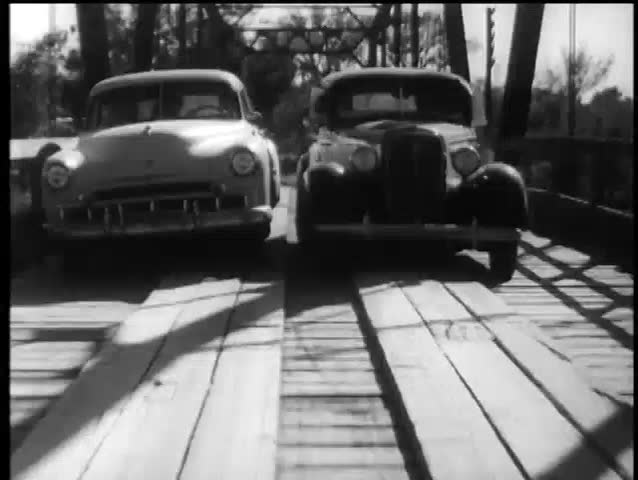 Two cars trying to pass on wooden bridge, 1960s