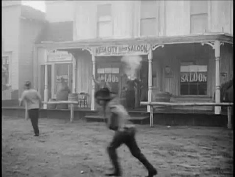 Wide shot of cowboys firing guns outside saloon, 1940s