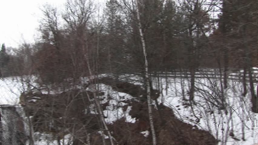 Pan left from rural winter landscape to dam next to a mill with waterwheel.