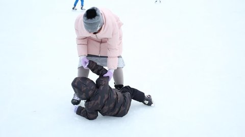 Woman helping her son to get up at the skating rink