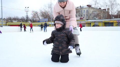 Woman straightens jacket on the child at the ice rink