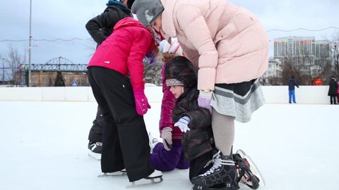 The woman and a four children skating together at ice rink