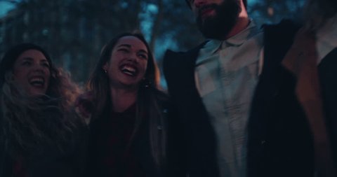 Group of young adult hipster friends smiling while walking in town on evening: film stockowy