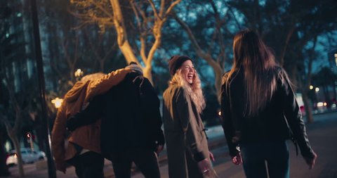 Young happy couples in winter outfits embracing while taking a night walk outside in the city