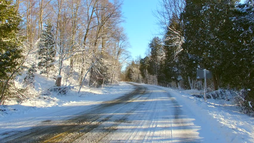 Moving down scenic rural road through snow covered forest in winter. Door County Wisconsin.