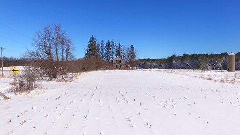 Scenic old, abandoned farm house with snow covered woods and fields, rural Wisconsin.
