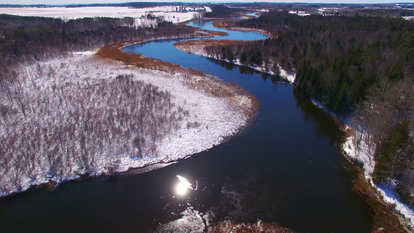 Aerial flyover of winding,icy Ahnapee River near Algoma Wisconsin in early Springtime.
