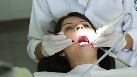 Dentist. Female dentist examining patient teeth with open mouth dental procedure