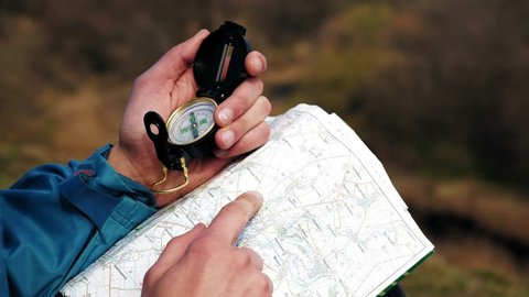 Man tourist in a blue jacket looking on the compass and map