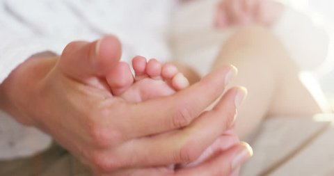 the hands of a mother gently touch her baby feet while breastfeeding