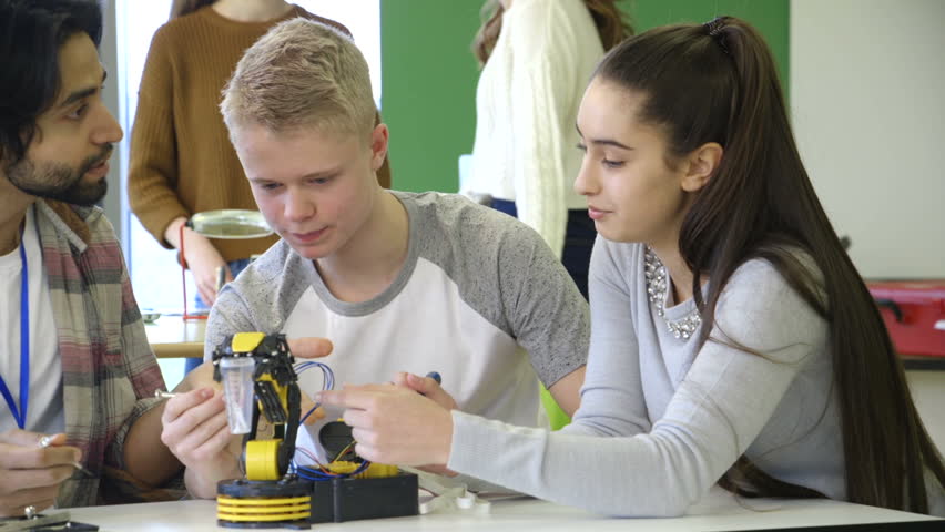 Young, male teacher helping his students build a robotic arm. Royalty-Free Stock Footage #15582925