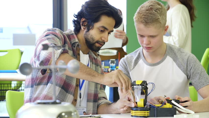 Young, male teacher helping his students build a robotic arm. Royalty-Free Stock Footage #15582943