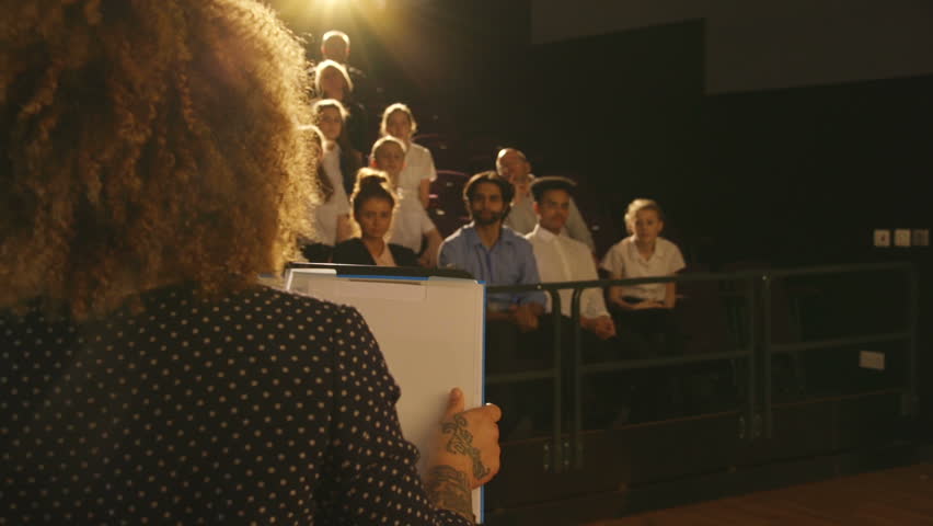 Over the shoulder view of a woman giving a presentation to a group of students and teachers in a school. Royalty-Free Stock Footage #15582961