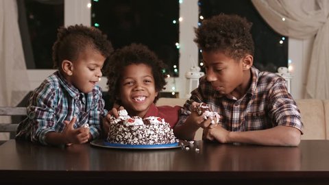 Three afro boys eating cake. Three black kids eat cake. Time for dessert. They waited for so long.