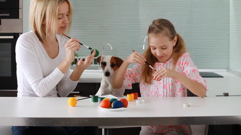 Mother with daughter painting eggs