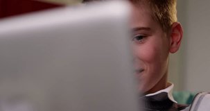 4k,Happy and cheerful young boy working on laptop computer at home. Slow motion.