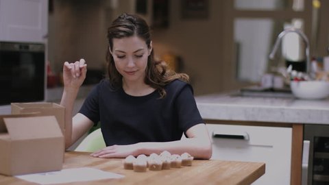 Young adult woman packing cupcakes at home in kitchen