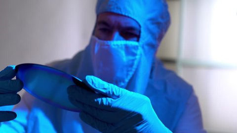 cleanroom tech checking out a silicon wafer microchip disk 4k