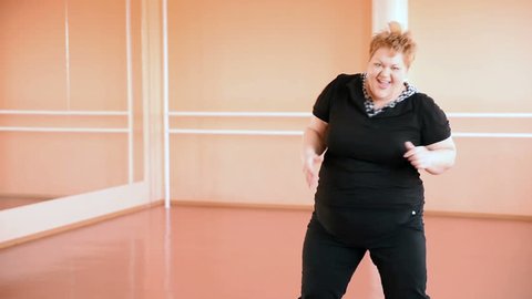 overweight girl is engaged in dances in the hall. cheerful plump, gymnastics and dance