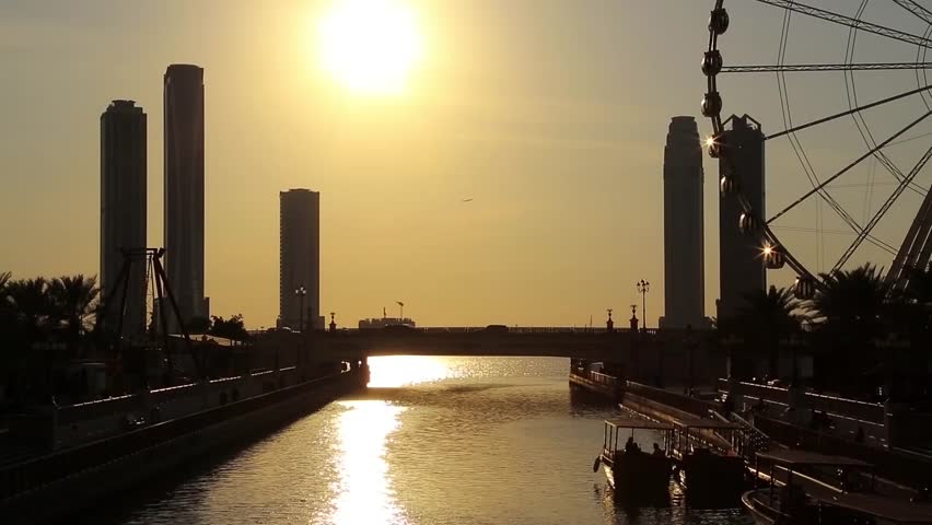 Sunset over Al Qasba canal and ferris wheel in Sharjah city, United Arab Emirates. Sharjah - third largest and third most populous city in UAE, after Dubai, and the capital of the emirate of Sharjah