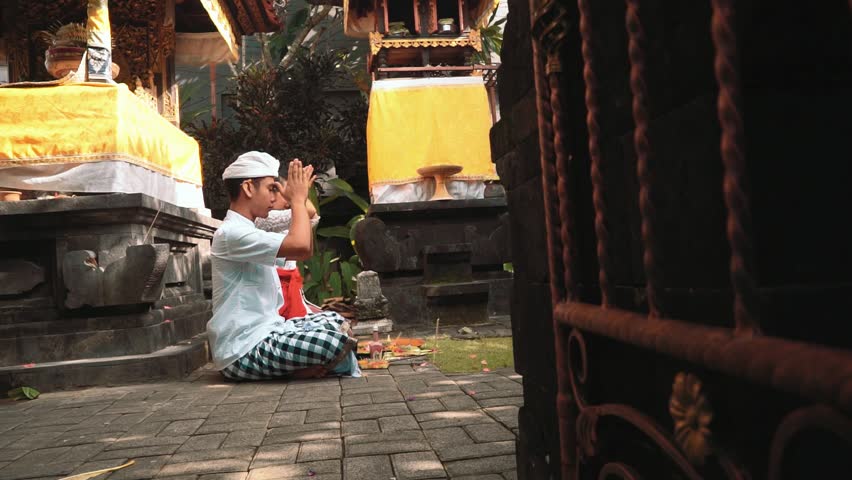 Young woman and man praying in a small balinese temple