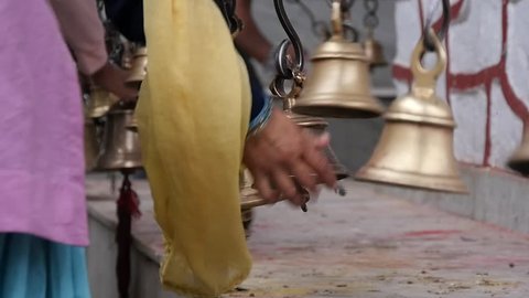 Woman's hand shaking a bell in Hindu temple