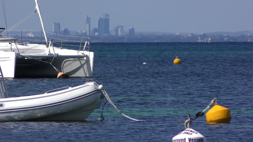 Scenic View of coastline Western Australia from Rottnest Island across Indian Ocean, with skyscrapers of Perth city at the horizon, yachts moored at buoys.