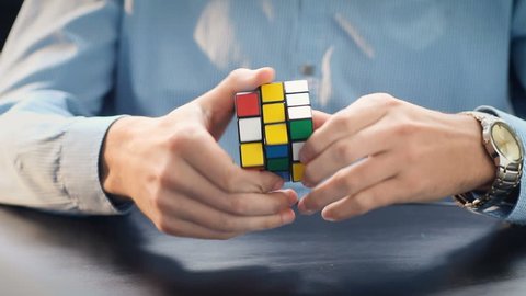 NEW YORK - APRIL 2: Businessman hands solving Rubik's cube puzzle on April 2, 2016. Rubics cube is the world's top-selling puzzle game and one of the world's best-selling toys.