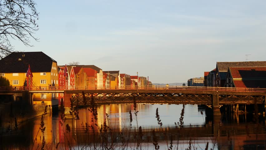 Peple on Bridge near famous wooden colored houses in Trondheim city, Norway