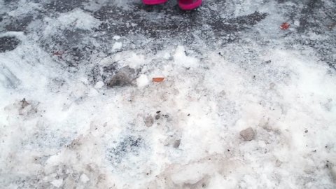 Little girl dressed in pink clothing cleans snow with plastic shovel.