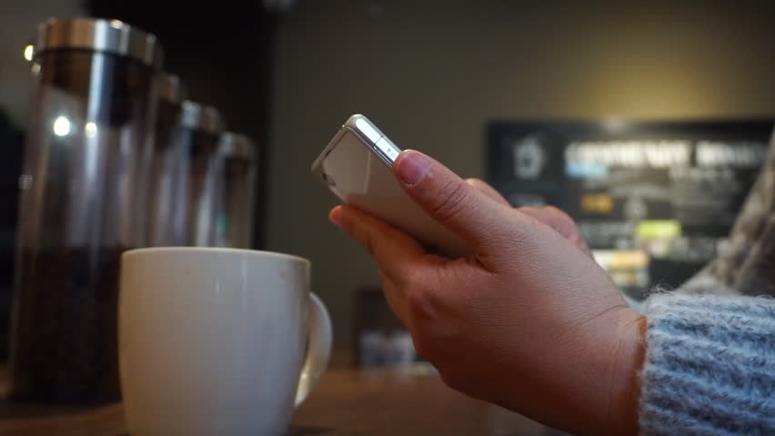 playing mobile phone and drinking coffee in cafe