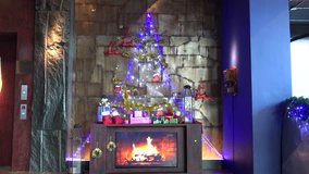 Christmas scene, decorative fireside with Christmas gifts and Christmas tree and glowing fire. Filmed in 4k.