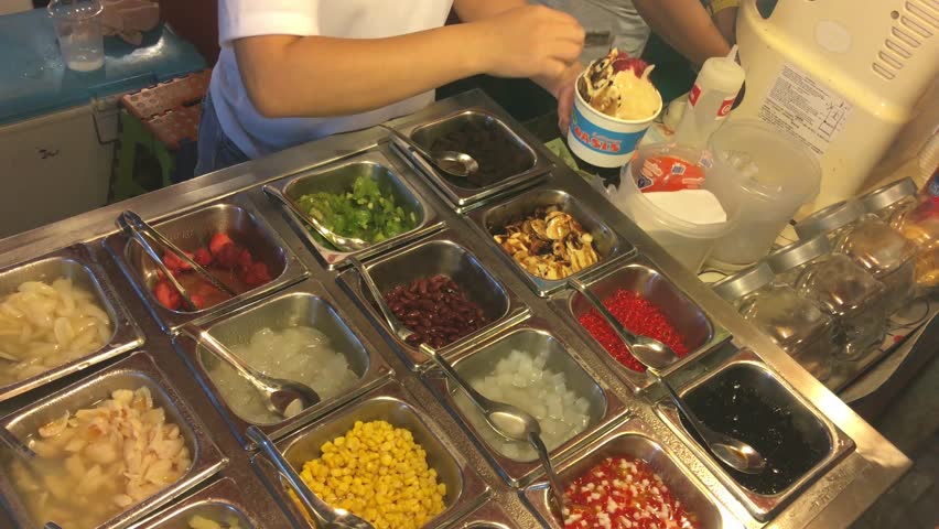 Ordering ice with fruits and pay on a market in Bangkok, Thailand