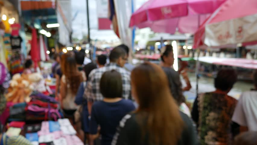 People walk, shop, eat and take photos around the Amphawa Floating Market. It is one of the most popular floating markets in Thailand. Some vendors sell food on their boats. 