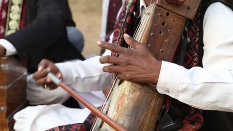 Udaipur, India - December 24, 2015 : Close up shot of traditional musical instrument called "Sarangi" (violin) playing by  Manganiars and Langas at a cultural fair at Shilpgram in Udaipur