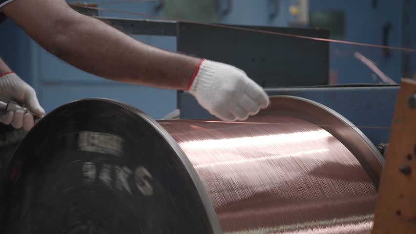 Man inspecting the quality of a copper wire as it is being spun into a cable  Inside a cable factory.  Royalty-Free Stock Footage #15640747