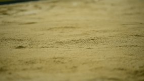 Athlete performing a long jump in the sand pit during athletics competition