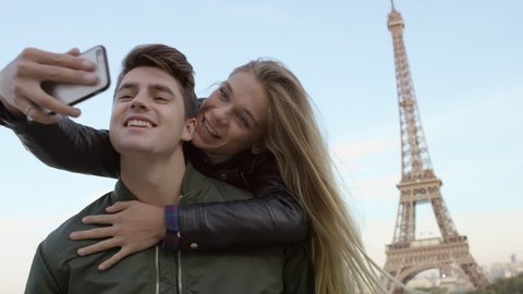 Couple visiting the Eiffel tower and taking selfies with each other. Paris, France