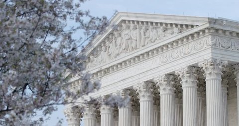 The US Supreme Court with cherry tree flower blooms rack focus. Equal Justice Under Law. Also available in 4K SLog HDR.