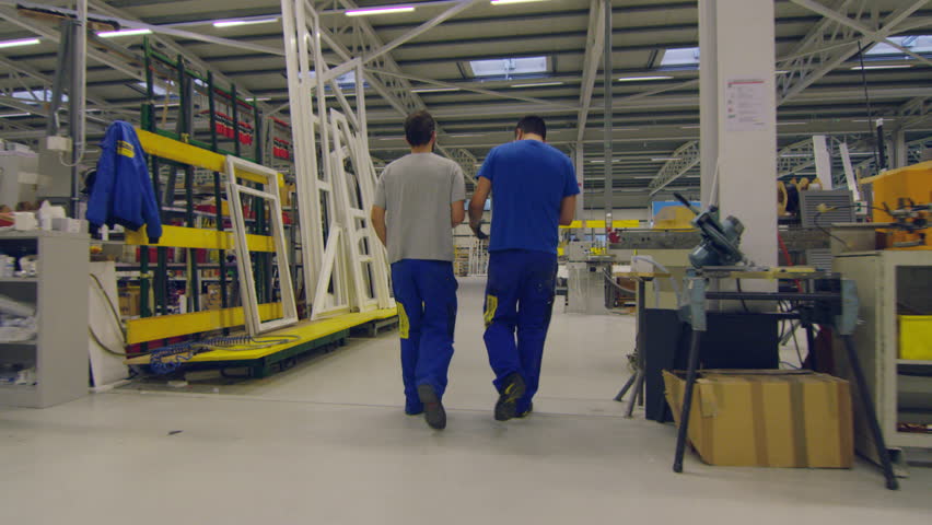 Two members of staff walking and talking while passing through the factory VD Le Marais, Switzerland October, 2015