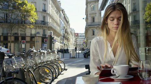 Young Lady working on her tablet while at a local cafe. Paris, France