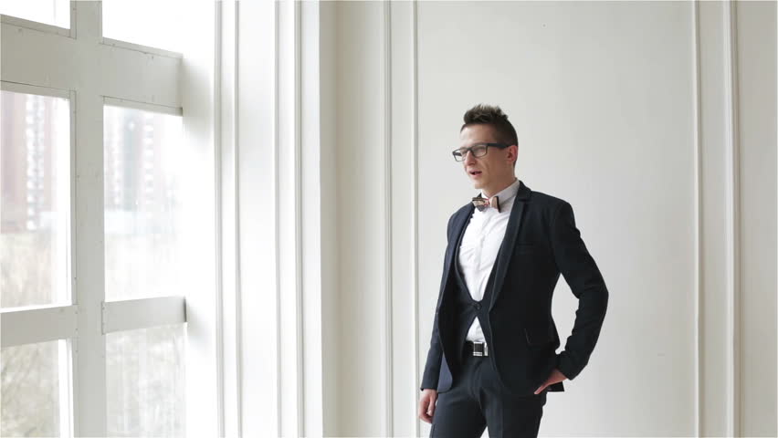 A young handsome man in glasses talking and laughing. Business outfit.
