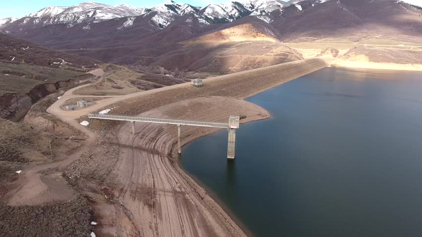 A beautiful aerial shot of a mountain reservoir lake and dam for storing water in Utah near Park City during a drought season