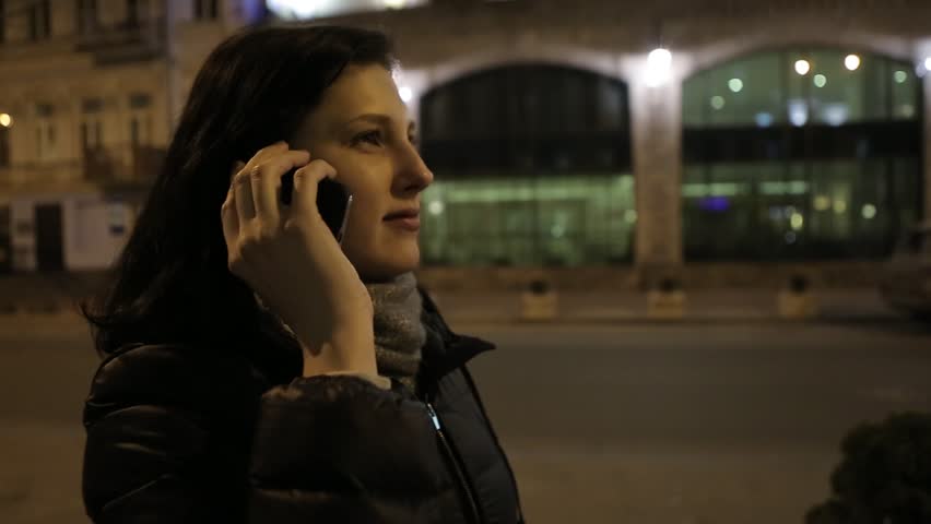 Girl Walking on the Road at Night Near the Phone Stores